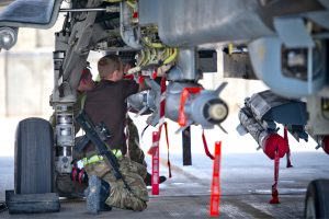 Engineer beneath the undercarriage of a military plane