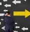 Person standing in front of arrows pointing in different directions