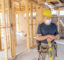 Builder, masked inside a building construction, leaning on a level