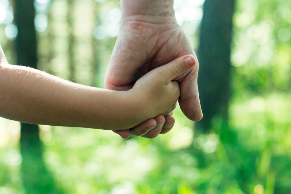 Adult hand holding a child's hand