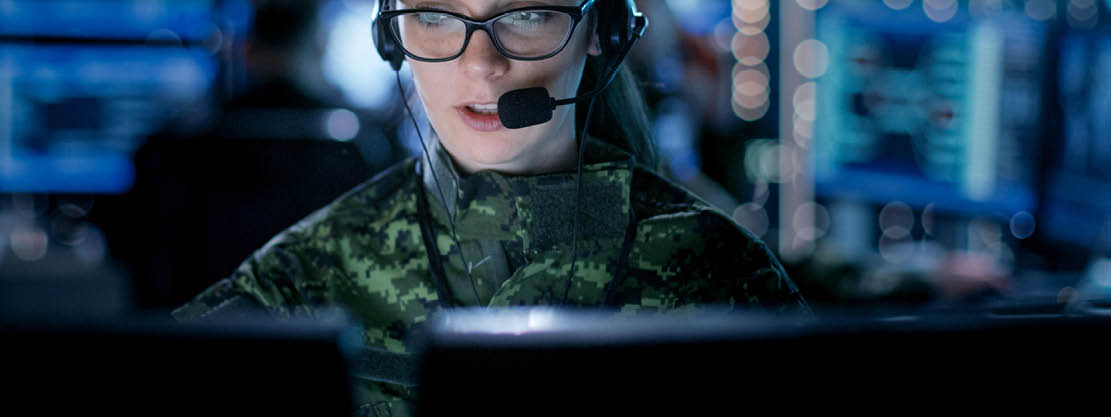 Female soldier wearing a headset and looking at a computer