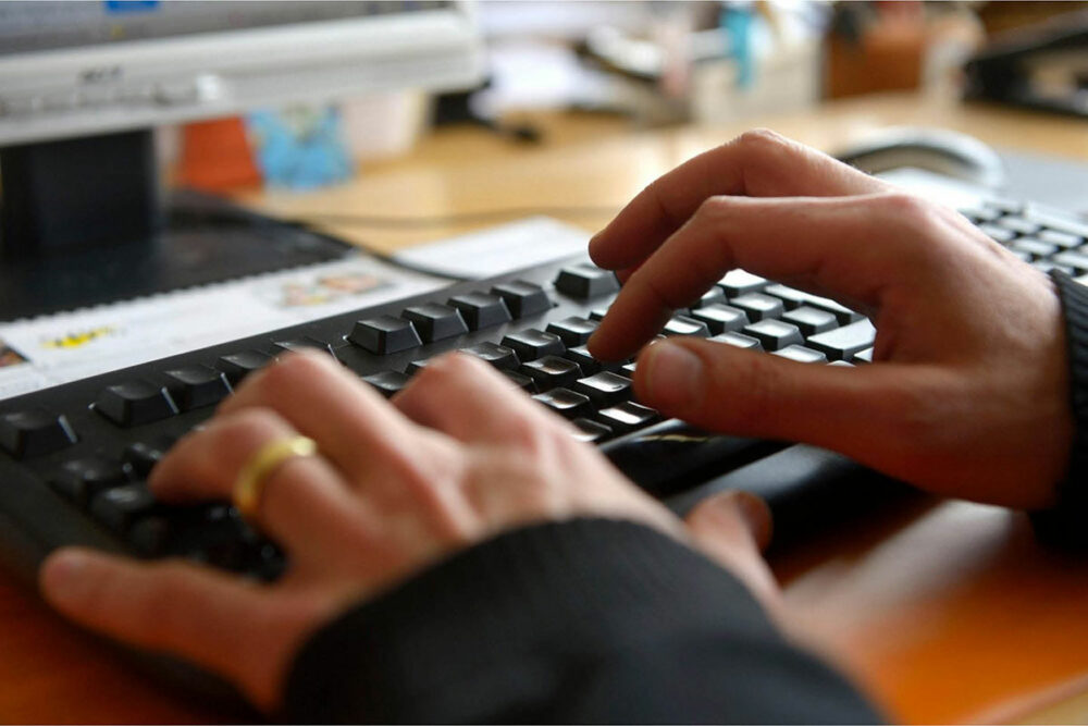 Hands typing on a computer keyboard