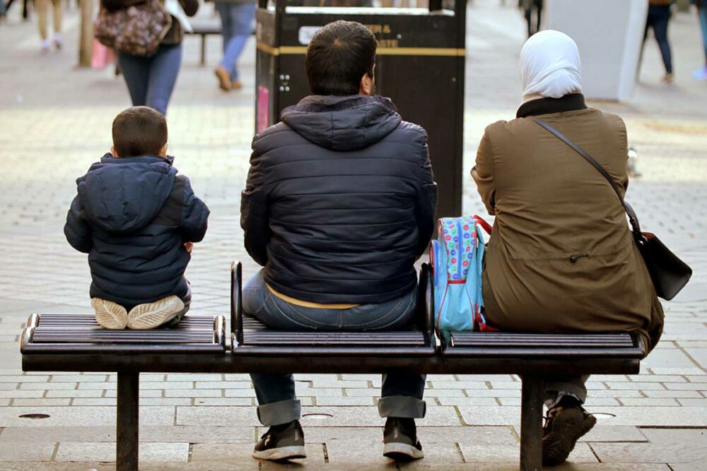 A man, woman and child sitting on a bench