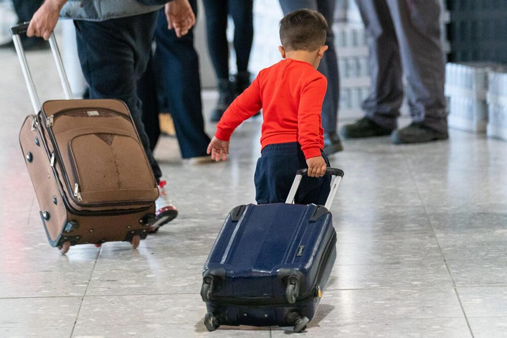 A young boy pulling a suitcase as refugees arrive from Afghanistan at Heathrow Airport, London.